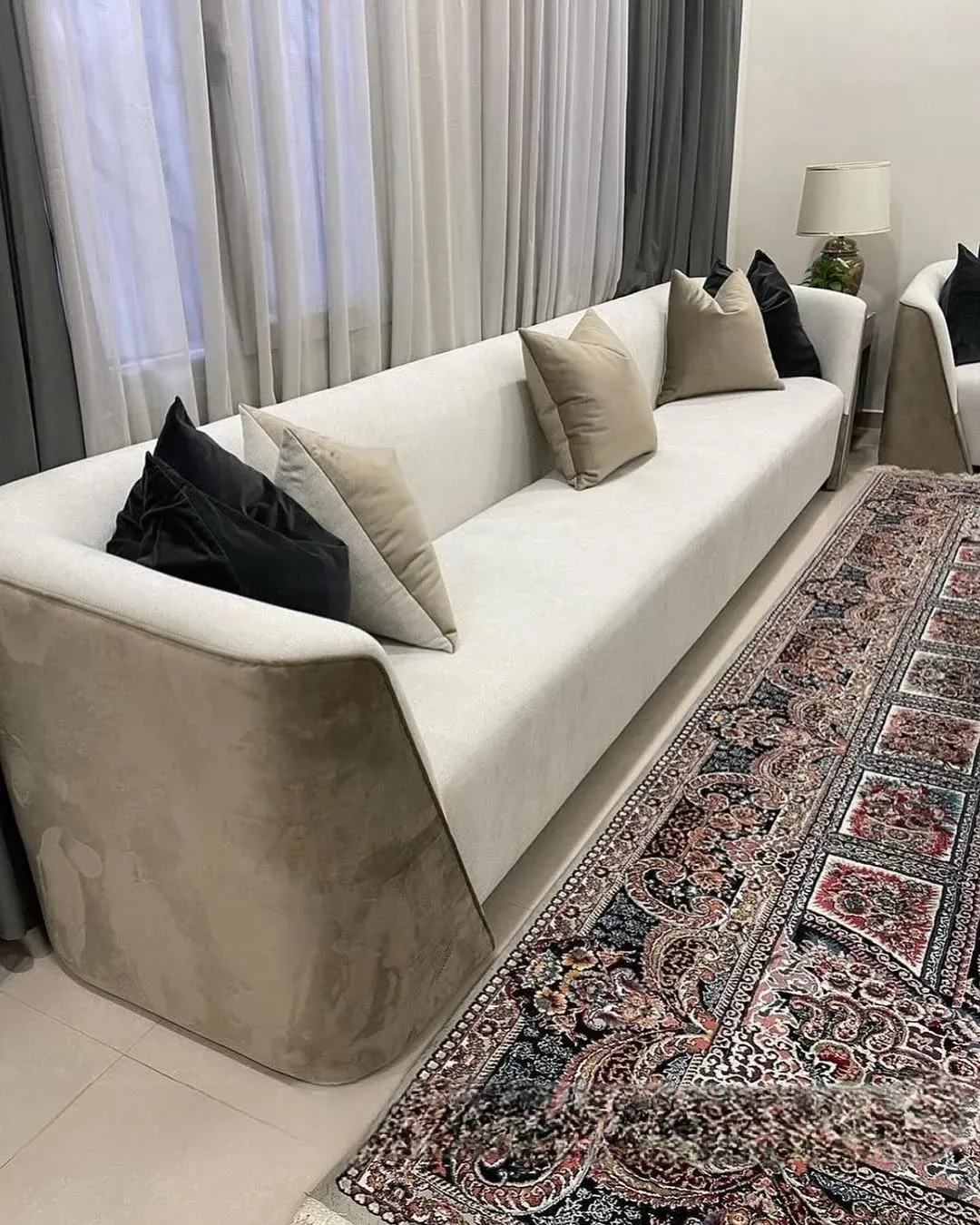 كنب مودرن بلونين بمقعد وظهر أبيض وإطار خارجي ملتف بقماش مخملي بيج غامق في صالة
